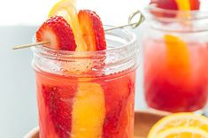 two mason jars filled with fruit and garnished with strawberries, lemons, and orange slices