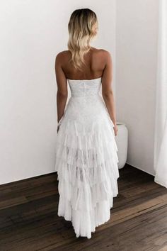 a woman standing in front of a toilet wearing a white dress