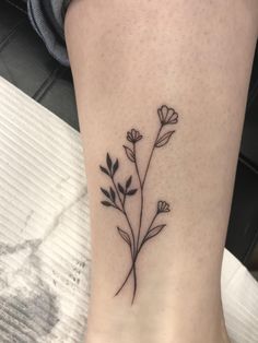 a black and white photo of a flower on the ankle, with small leaves in it