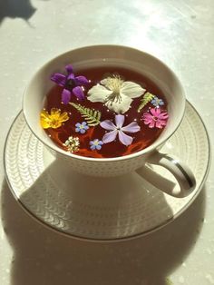 a cup filled with liquid and flowers on top of a saucer