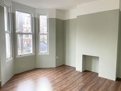 an empty room with hard wood floors and windows