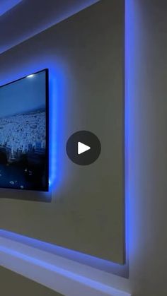 a flat screen tv mounted to the side of a wall with blue lights on it