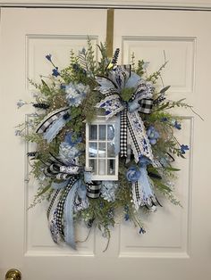 a blue and white wreath with a lantern hanging on the front door to welcome guests