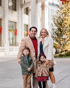 a man, woman and two children standing in front of a christmas tree