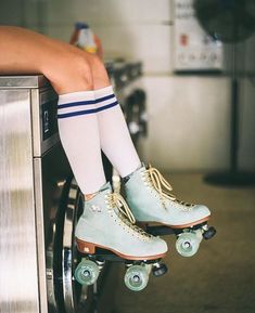 a person wearing blue roller skates sitting on top of a washing machine in a kitchen