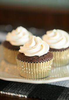 chocolate cupcakes with white frosting sitting on a piece of parchmented paper