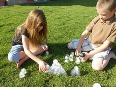 two children playing with plastic bottles in the grass