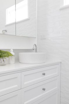 a bathroom with white cabinets and a large mirror on the wall over the sink,