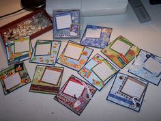 many cards are laid out on the table next to a sewing machine and thread spool