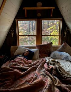 a person laying on a bed under a window in a room with wooden walls and ceilings