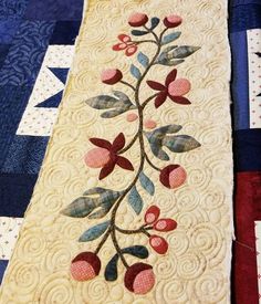 a quilted table runner with flowers and leaves on it