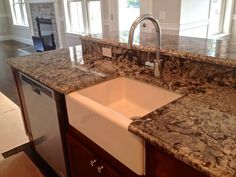 a kitchen with granite counter tops and white sink in the center, surrounded by wooden cabinets