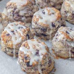 blueberry muffins with icing sitting on top of a baking sheet, ready to be eaten