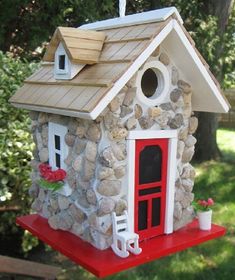 a bird house made out of rocks with a red door and window on the roof