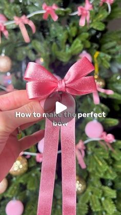 a person holding a pink ribbon in front of a christmas tree with ornaments on it