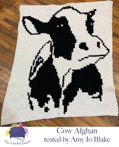 a black and white crocheted cow is featured on the cover of a blanket