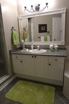 a bathroom with a green rug on the floor and a white sink in front of a large mirror