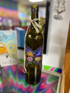 a bottle with a butterfly painted on it sitting on a table next to other items