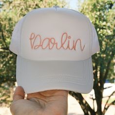 The perfect Darlin trucker hat! The trucker hat is embroidered in pink thread using a western rope font.  About the Hat: White foam with mesh back. Snapback closure. Rope Font, White Dad Hat, Hurley Hats, White Trucker Hat, White Bucket Hat, Desert Bloom, Pink Thread, Minnie Mouse Bow, Wide Brim Fedora