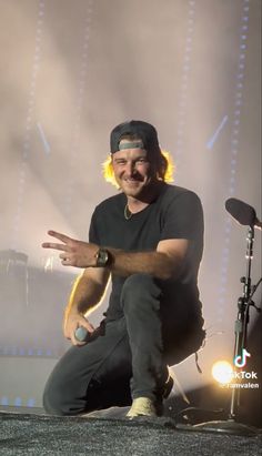 a man sitting on top of a stage with his hands out in front of him