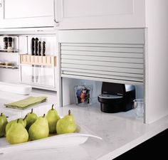 a kitchen with white cabinets and pears on the counter