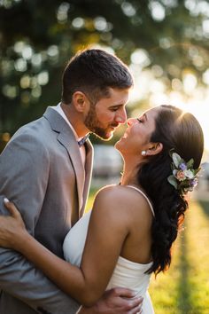 a bride and groom embracing each other in front of the sun on their wedding day