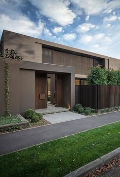 a modern house is shown with grass and shrubs on the front lawn, along with an empty street