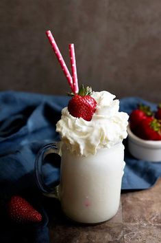 two strawberries sit on top of a whipped cream drink