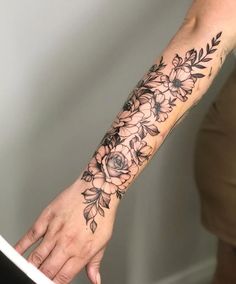 a woman's arm with flowers and leaves on it