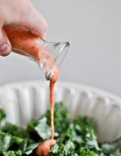 a person pouring dressing into a bowl with carrots and spinach in it on instagram