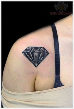 a woman's shoulder with a diamond tattoo on her left side ribcage