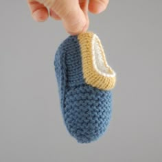 a hand holding a knitted blue and yellow object with a white stripe on it