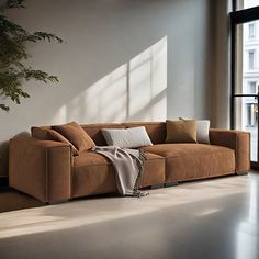 a brown couch sitting next to a window in a living room