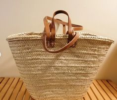 a large woven basket sitting on top of a wooden table next to a white wall