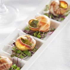 four appetizers in small trays on a white tablecloth with wine glasses