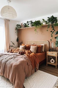 a bedroom with plants on the wall and a bed covered in brown sheets, blankets and pillows