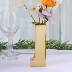 there is a vase with flowers in it and two wine glasses on the table next to it