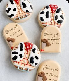 four decorated cookies with different designs and sayings on them, sitting on a sheet of paper