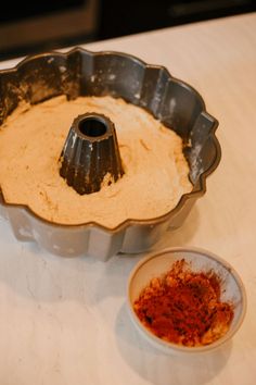 a cake pan with some red stuff in it next to a bowl on the table