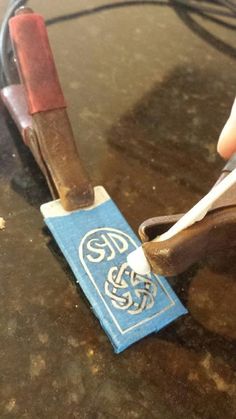 a pair of scissors are being used to cut paper on a piece of wood that is sitting on a table