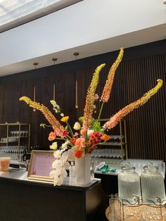 a vase filled with flowers sitting on top of a counter next to a glass case