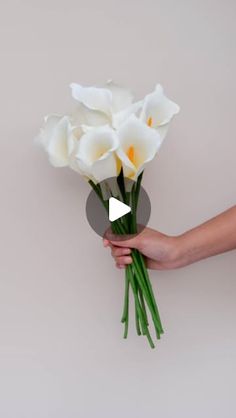 a person holding white flowers in their hand