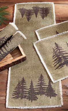 three placemats with trees on them are sitting on a wooden table next to a knife and fork