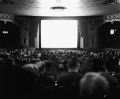 an auditorium full of people sitting and standing in front of a large window