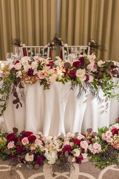 an arrangement of flowers and greenery decorates the head table at a wedding reception