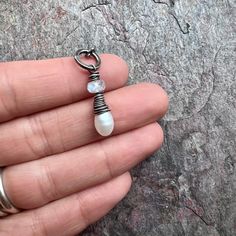 A genuine freshwater pearl has been wrapped in sterling silver. Above the pearl sits a small rainbow moonstone rondelle. The pendant dangles from a hammered sterling silver bail which has been formed, soldered, and textured by hand. The silver has been oxidized and polished to create an aged patina finish.Be sure to see all photos and video for size and color reference. Rainbow Moonstone: About 4x6mm Pearl: About 6.5x10mm An optional chain can be added to this pendant. If you would like a chain Silver Moonstone Jewelry With Pearl Drop, Moonstone Jewelry With Pearl Pendant, Moonstone Pearl Pendant Jewelry, Handmade Teardrop Moonstone Necklace, Handmade Silver Moonstone Beaded Necklace, Artisan Adjustable Moonstone Necklace, Artisan Moonstone Pendant Jewelry, Carnelian Pendant, Silver Pearl Necklace