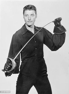 a man holding a baseball bat and glove in his right hand while posing for the camera