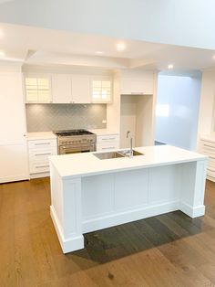 an empty kitchen with white cabinets and wood floors