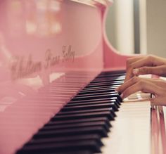 a person's hand on the keys of a pink piano