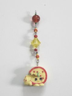 a necklace with an elephant and beads hanging from it's side on a white surface